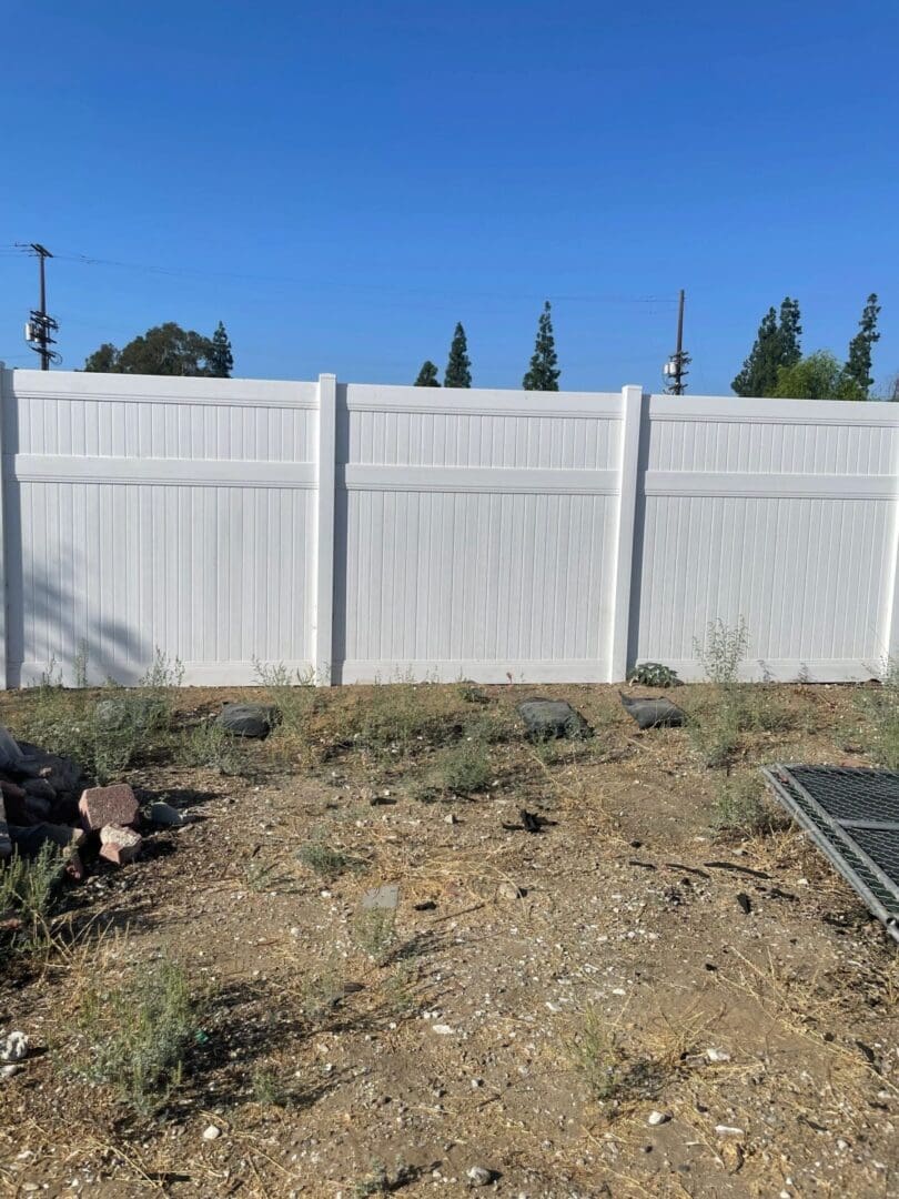 White fence with dry, sparse vegetation.