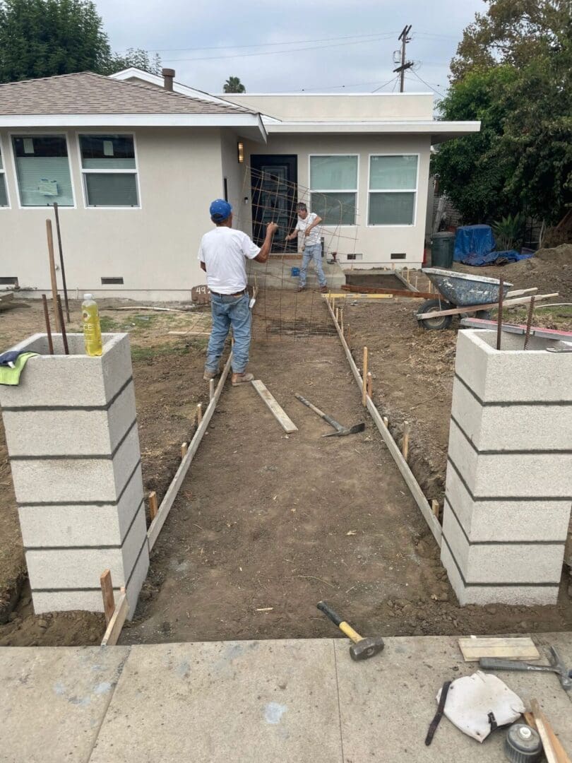 Workers constructing pathway in front of house.