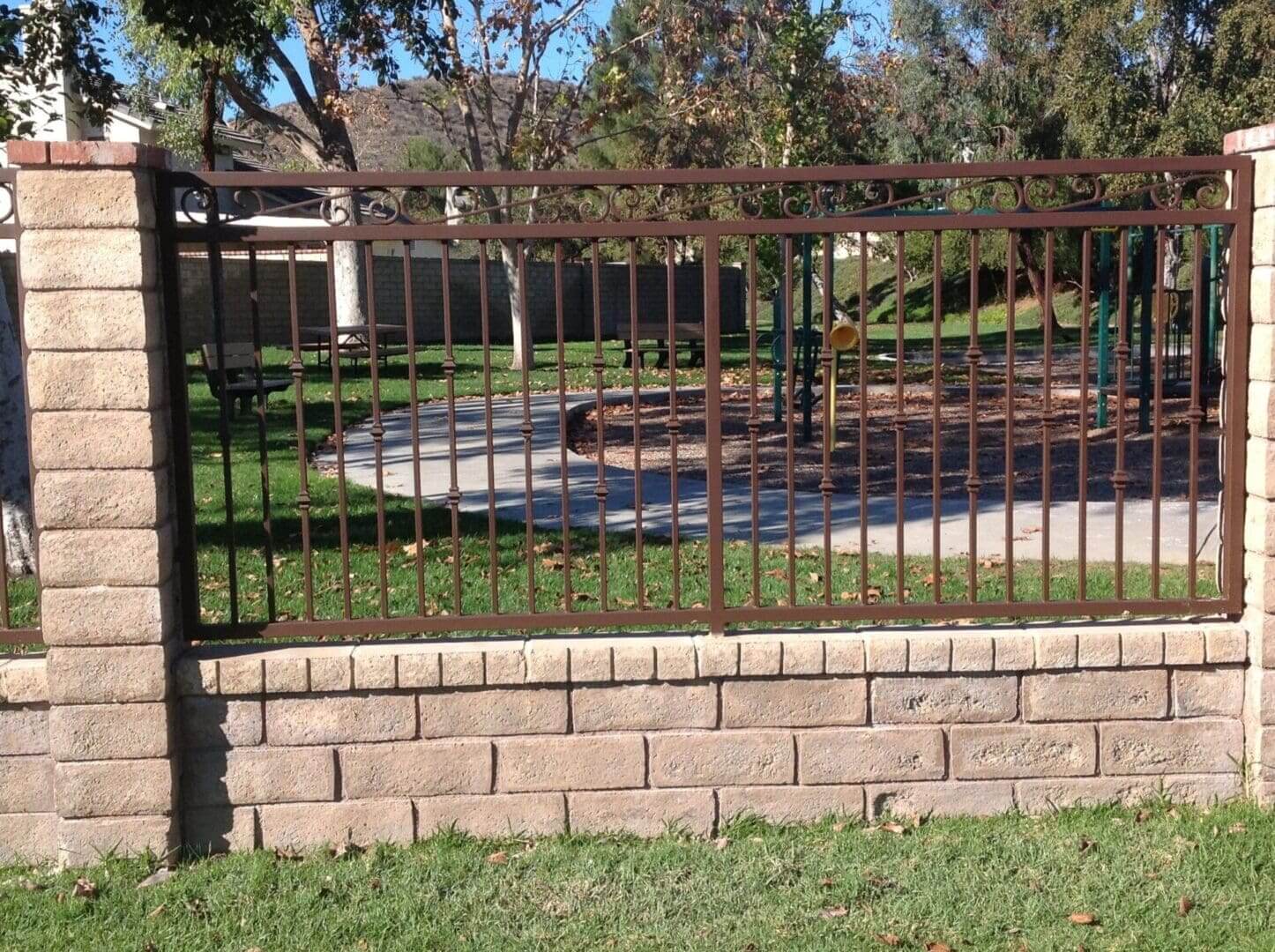 Brick fence with metal bars in park.