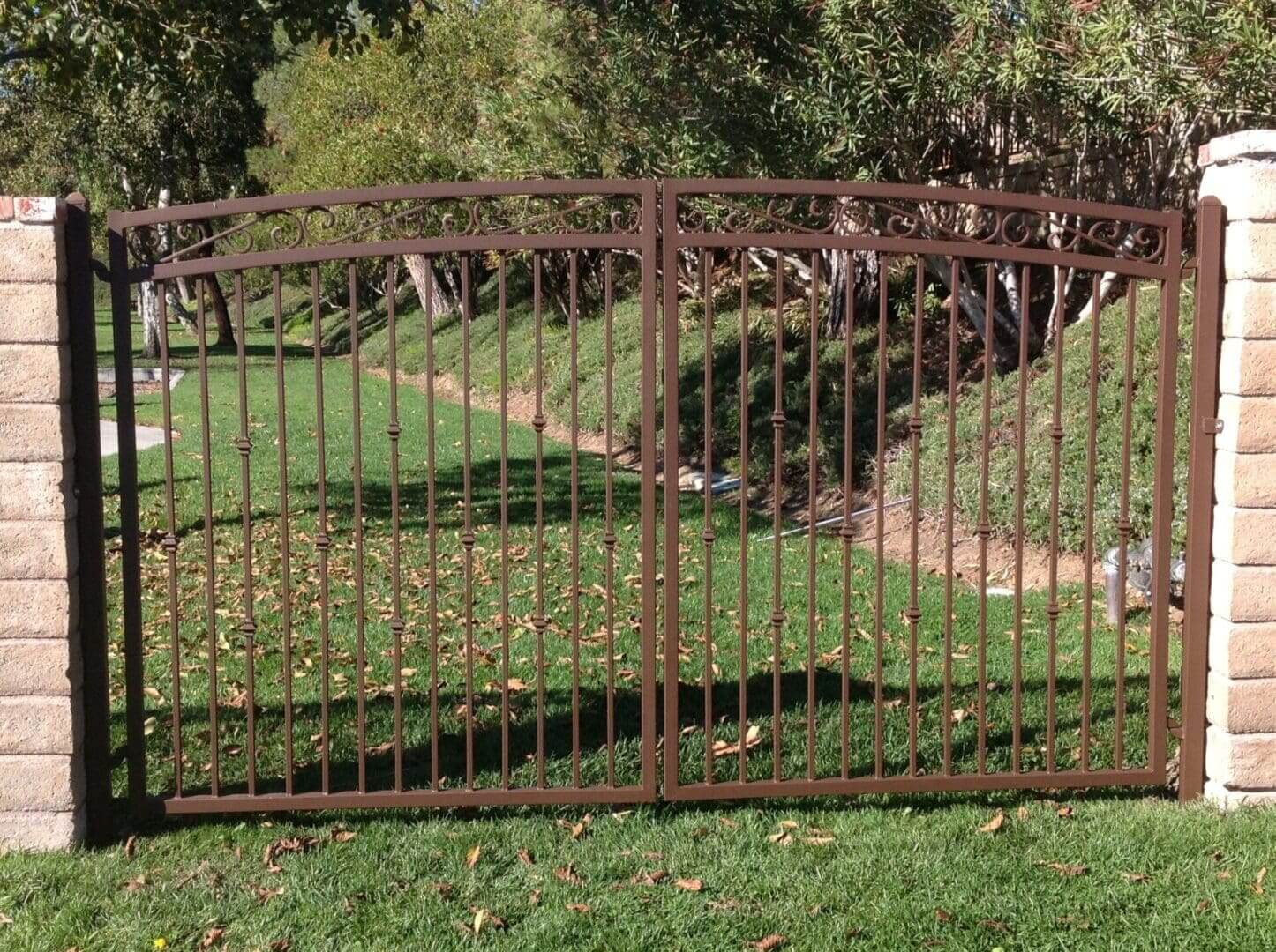 Brown metal gate in a garden setting.