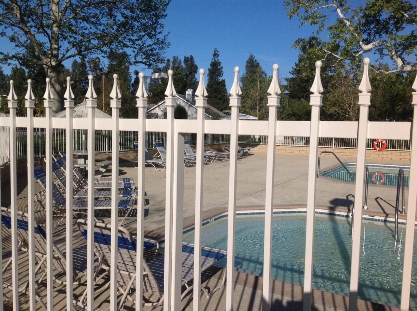 Pool area behind a decorative white fence.