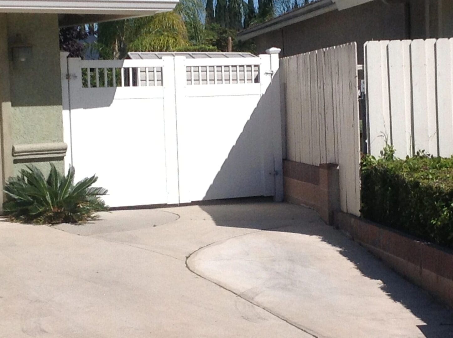 White gate and wooden fence in driveway.