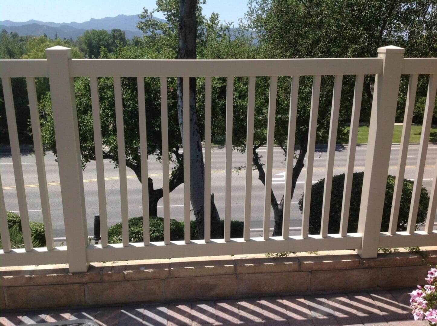 White fence overlooking road and trees.