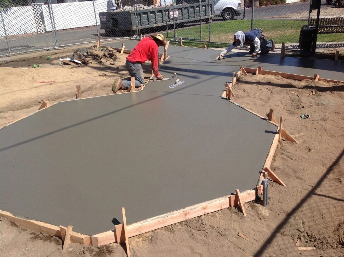 Workers leveling freshly poured concrete slab.