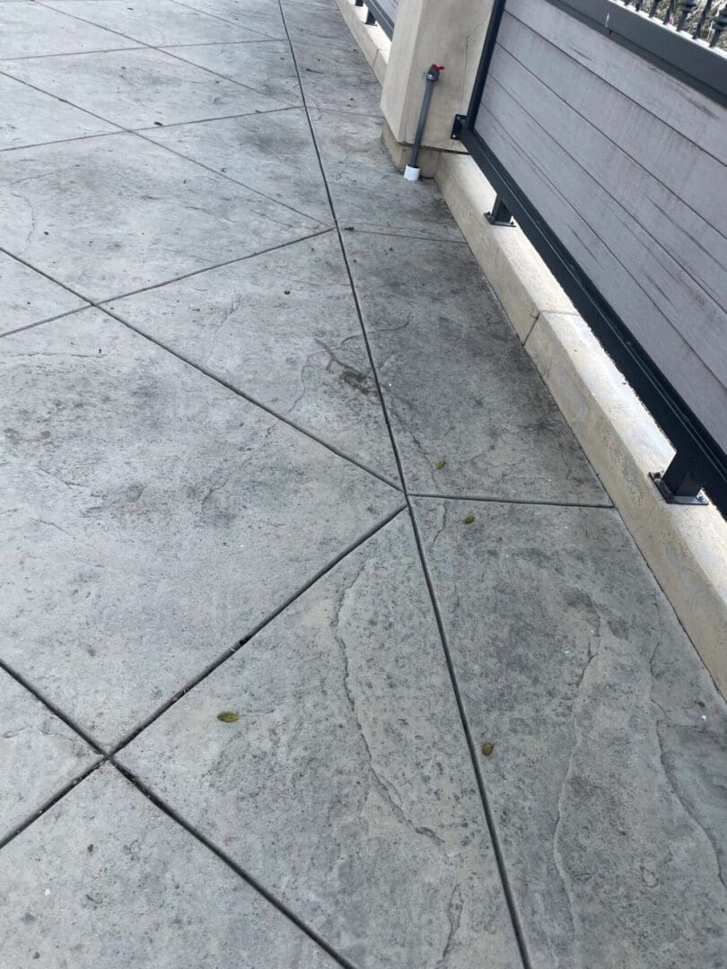 Concrete walkway with diagonal lines and railing.