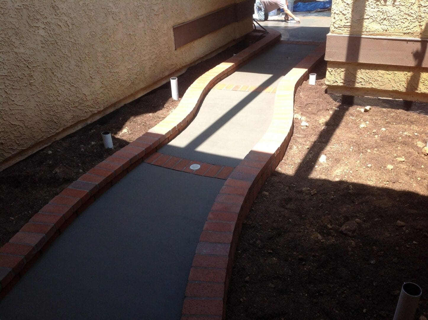 Curved concrete path with brick edges.