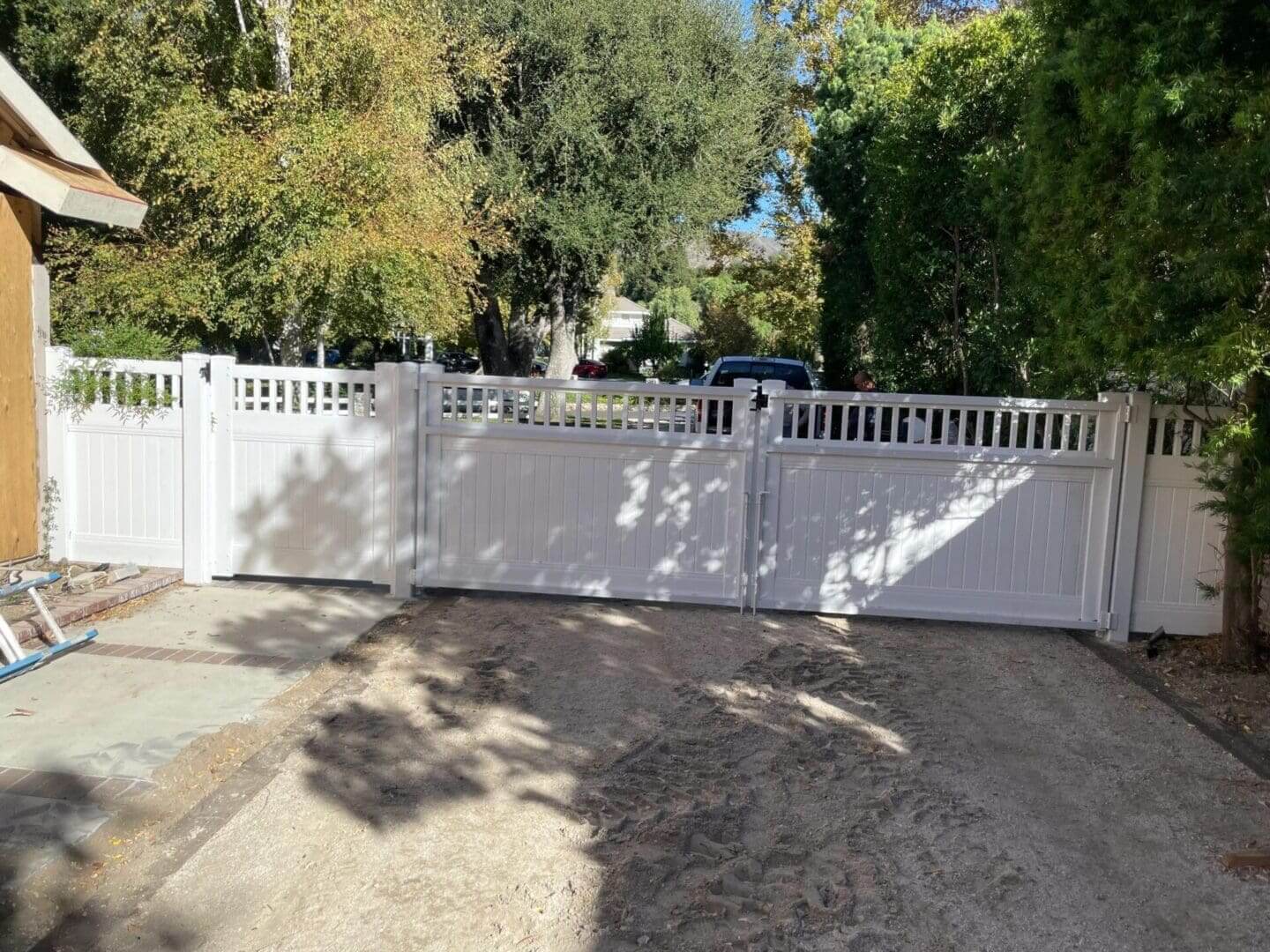 White fence gate with surrounding trees.