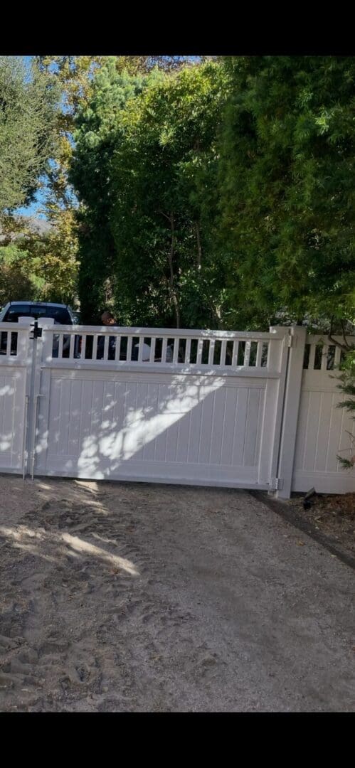 White gate with trees in background.