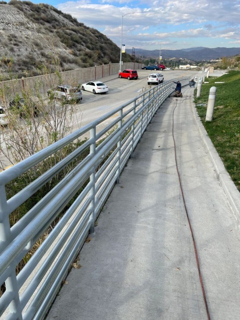 Sidewalk beside road with passing cars.