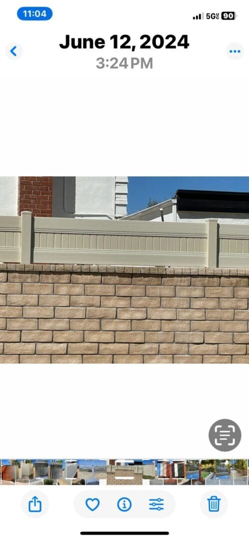 Brick and wood fence against house backdrop.