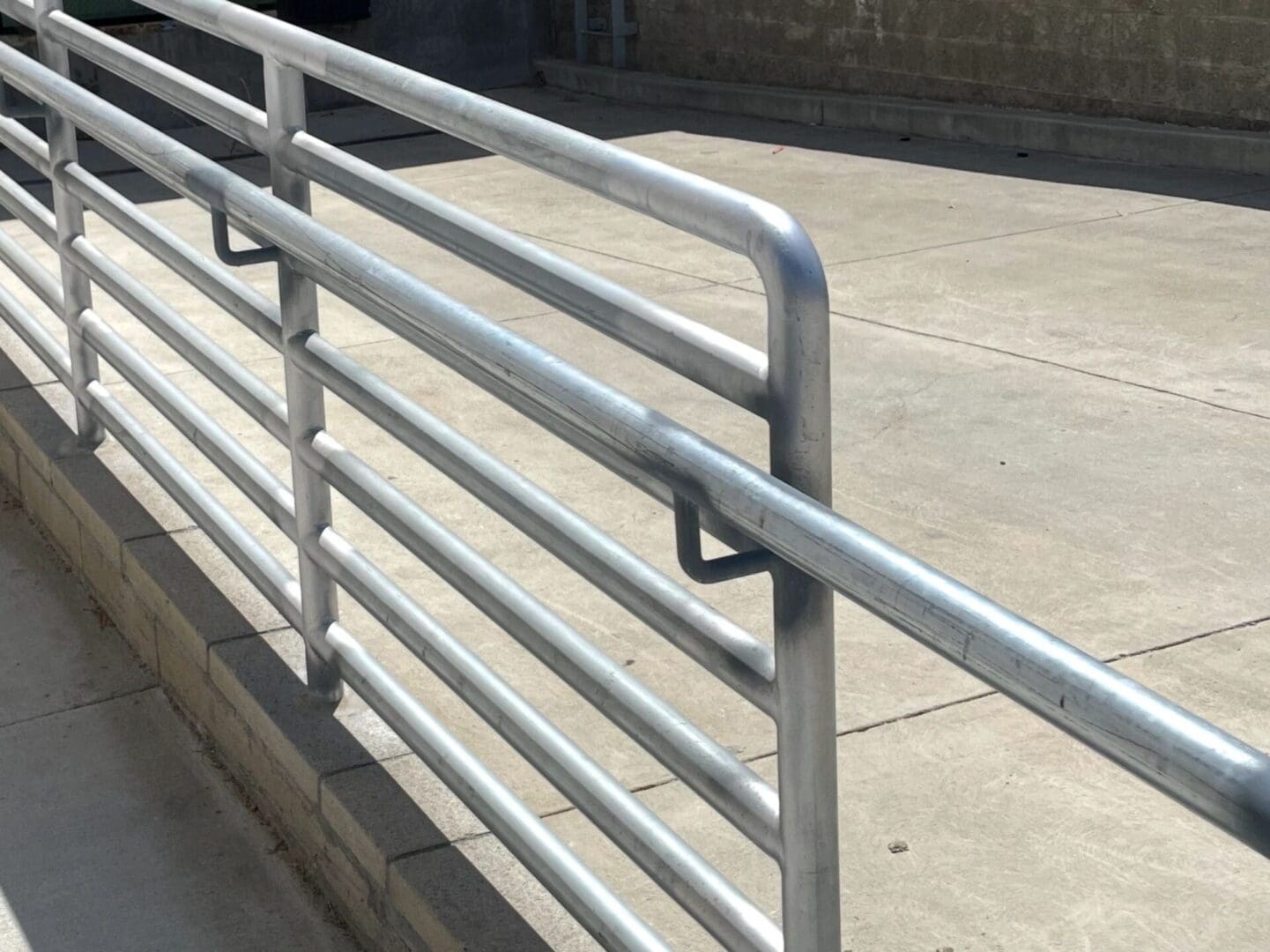 Metal railing beside concrete sidewalk.