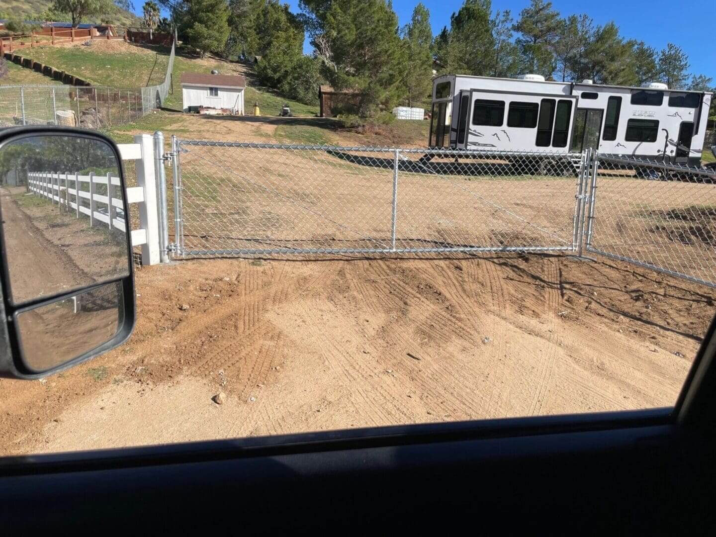 Chain link fence and parked RV in field.