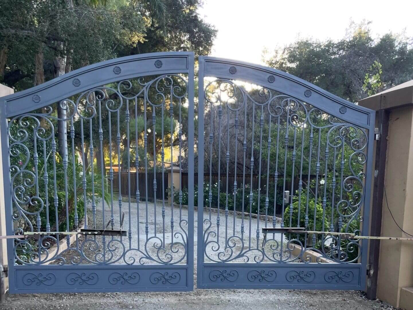 Ornate metal gate with garden background.