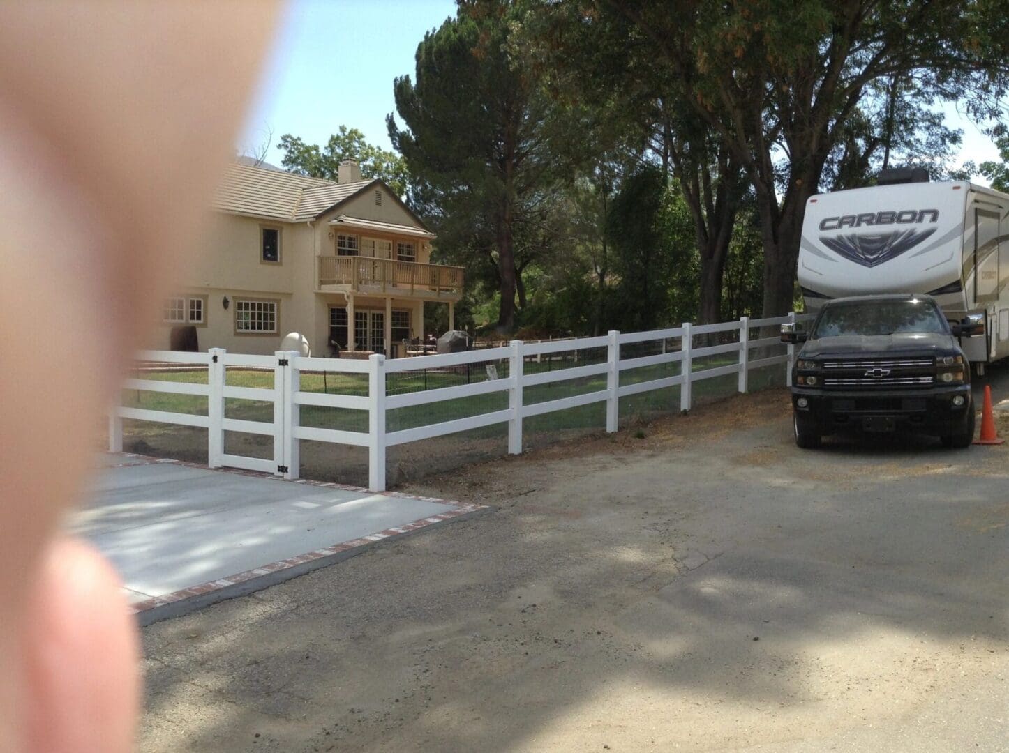 House, fence, RV, and trees in background.
