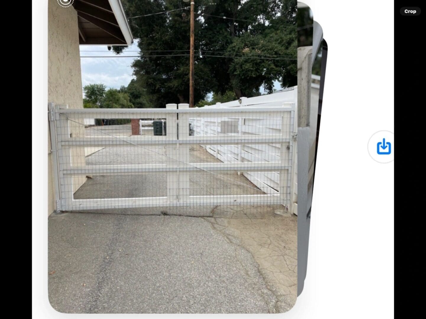 White wooden gate on paved driveway.