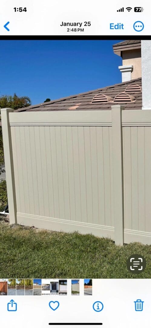 Beige fence beside house with tiled roof.