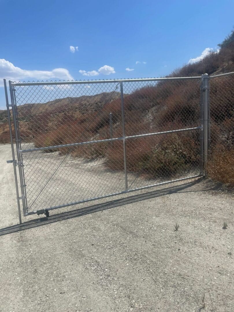 Chain-link gate across dirt road.