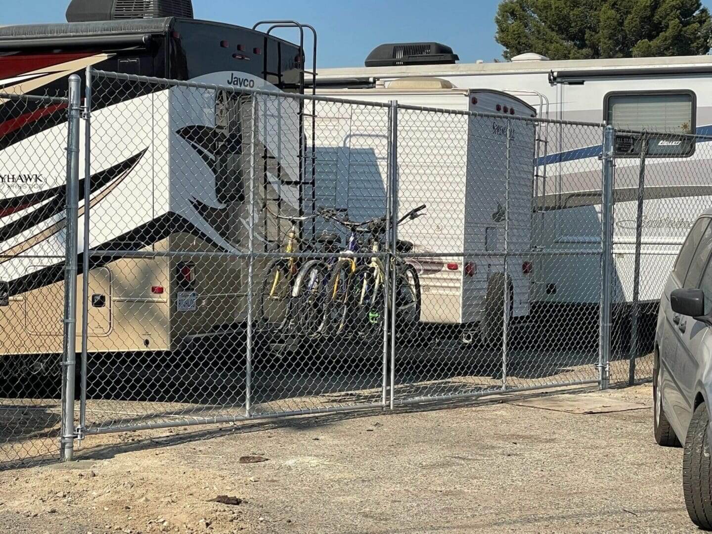 RVs and bicycles behind a chain-link fence.