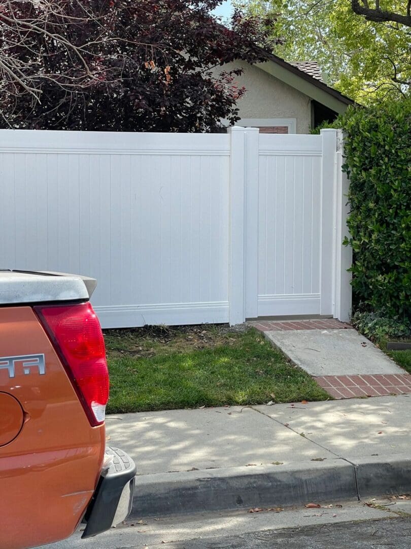 White fence with small gate and truck.