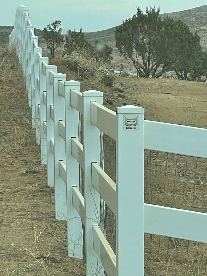 White fence along a rural dirt path.