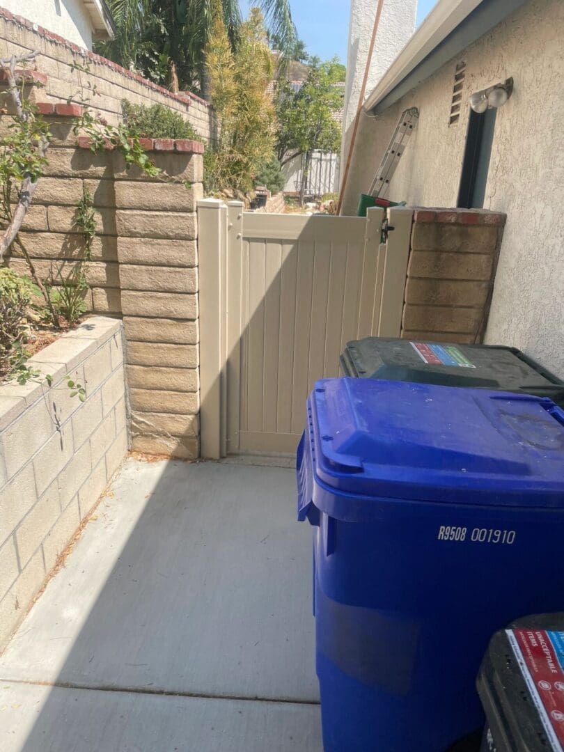 Side yard with gate and recycling bins.