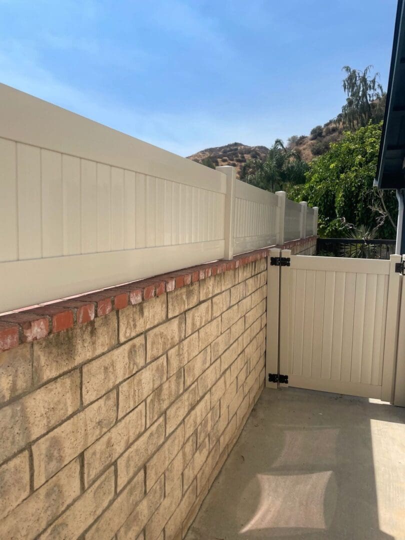 Brick wall with white vinyl fence gate.