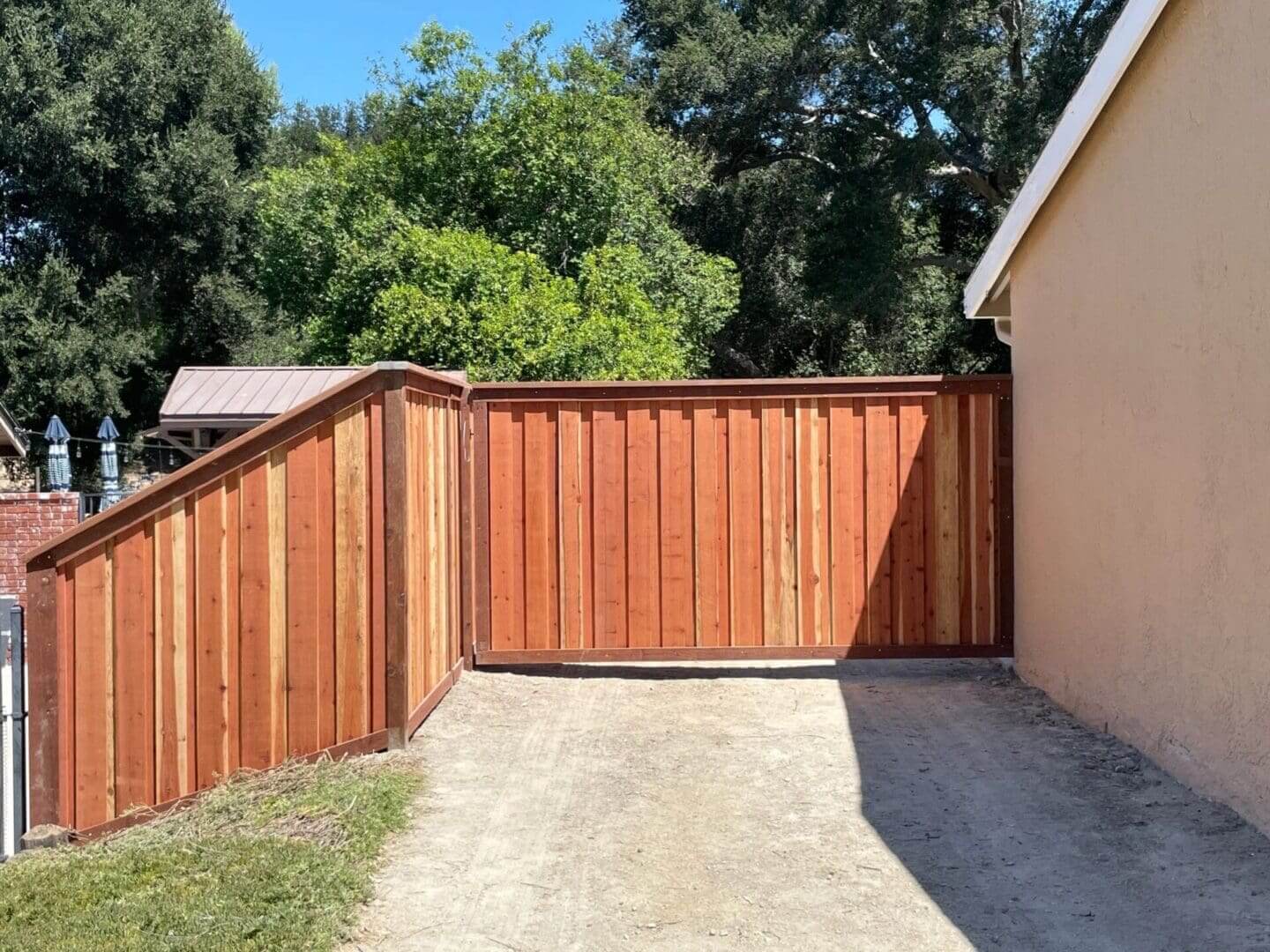 Wooden fence beside beige building and trees.