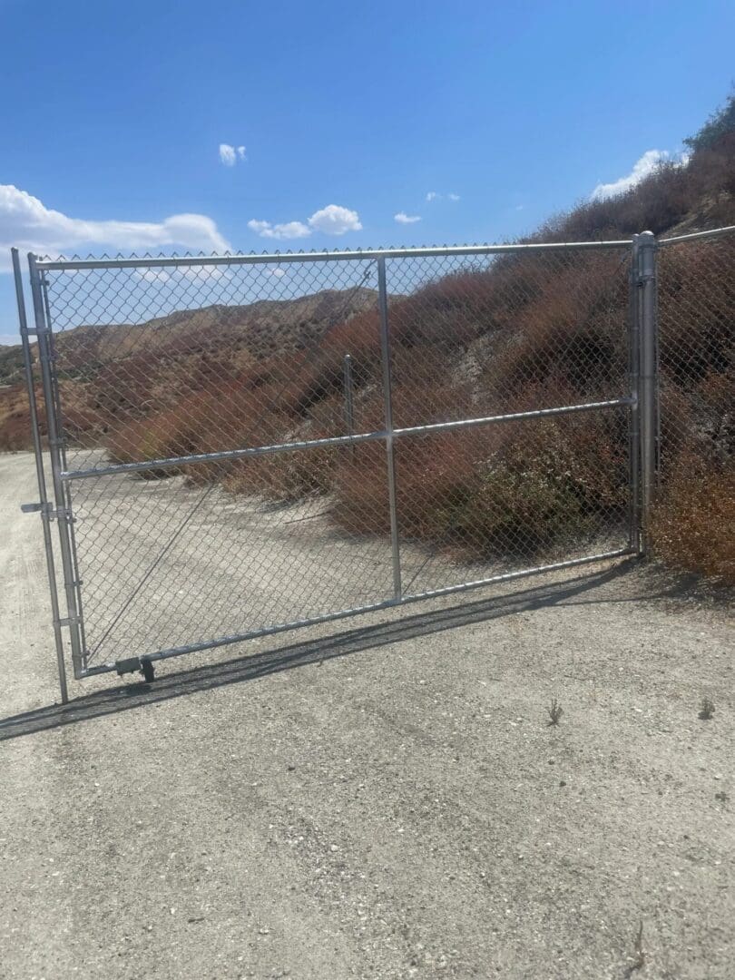 Chain-link gate blocking dirt road.